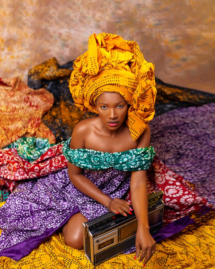 Captivating portrait of a Nigerian woman in vibrant traditional clothing and headwear with a vintage radio.