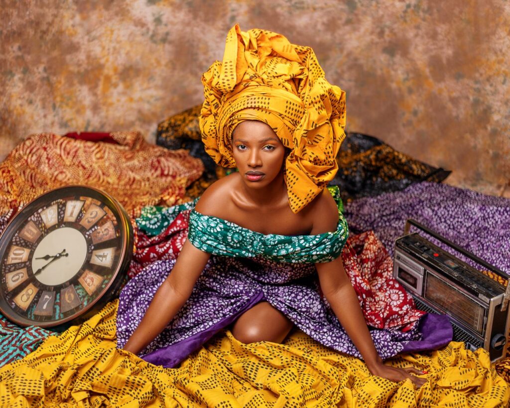 Colorful portrait of a young African woman sitting in traditional clothing and turban