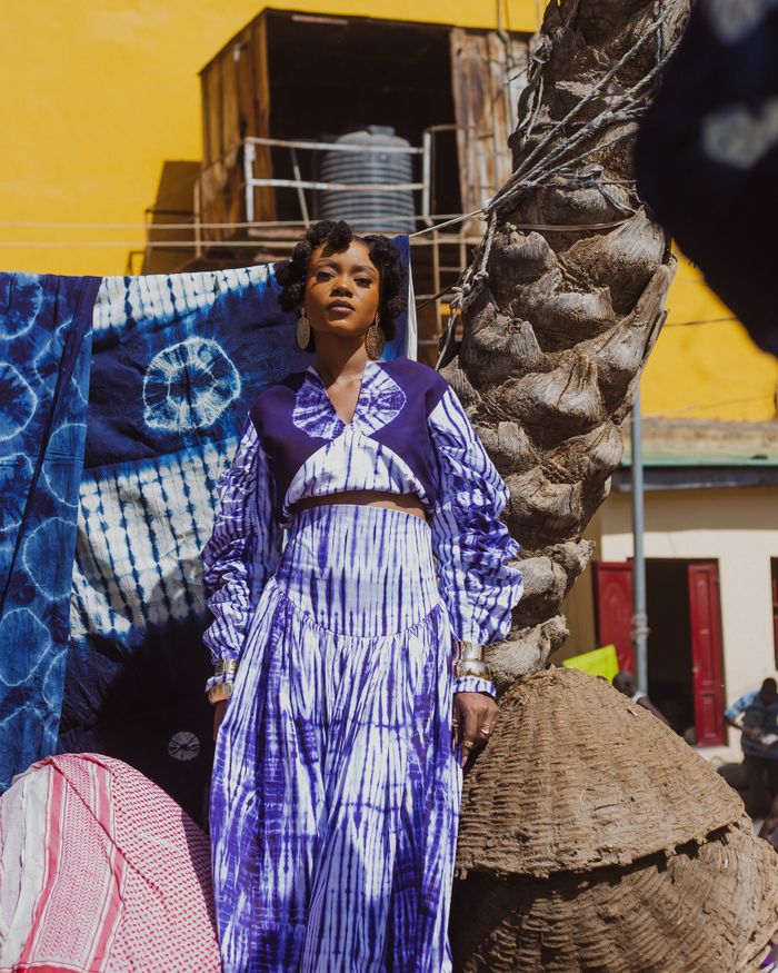 Vibrant portrait of woman in tie-dye fashion amidst urban backdrop.