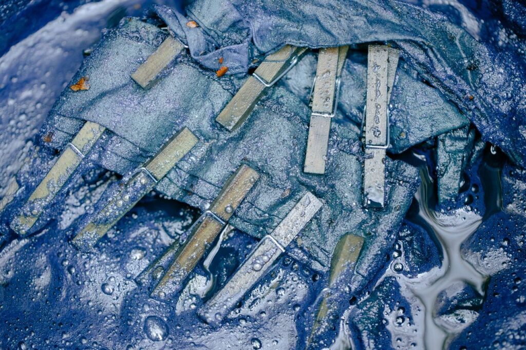 Detailed close-up of wet clothespins attached to blue fabric, highlighting textures.